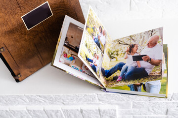 Luxury wooden photo book, wooden box with summer photos printed and flash card on linen natural background. Family memories photobook. Save your summer vacation memories. Photo album with wooden cover