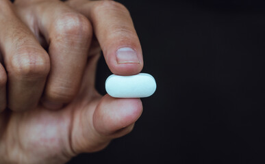 Young human hand holding white pills. International Day against Drug Abuse.Stop drug addiction concept.