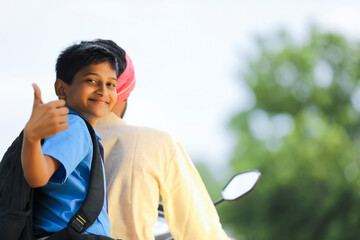 Young indian farmer dropping his child to school.