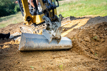Fototapeta premium Mini Excavator bucket closeup during work on construction site