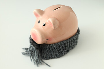 Piggy bank with knitted scarf on white background