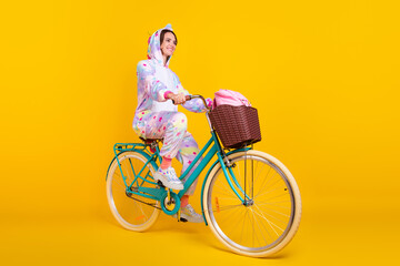 Full length photo of happy positive young woman ride bike smile good mood isolated on yellow color background
