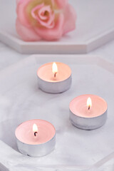 Romantic composition of pink candles and rose on white stone stands