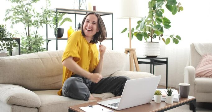 Crazy woman having fun dancing on sofa while working from home