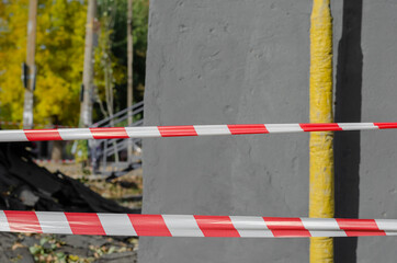 Red and white barrier tapes opposite the gas line and gray wall.