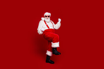 Fototapeta na wymiar Photo of funky lucky retired man wear santa claus costume smiling pwalking rising fists isolated red color background