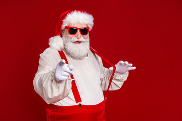 Fototapeta na wymiar Photo of funny cool man pensioner dressed santa claus costume arms hands suspenders empty space smiling isolated red color background