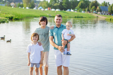 Fototapeta na wymiar caring young Caucasian father and his sons are walking in nature and breathing fresh air. Loving dad and little children have fun playing and talking