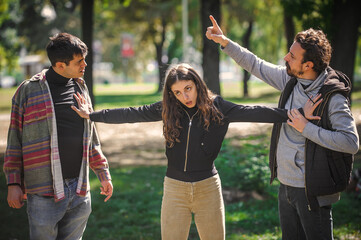 Fototapeta premium Woman with outstretched arms tries to separate men in quarrel