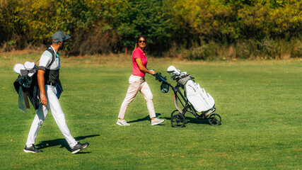 Golfing lifestyle couple walking on the golf course, enjoying a beautiful autumn day