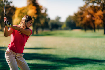 Golfing lady in a golf swing, shot from behind