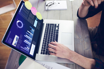 Hands of caucasian businessman sitting at desk, using laptop with statistical data on screen