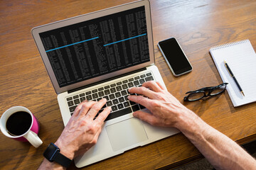 Hands of caucasian male programmer sitting at desk, using laptop with coding on screen