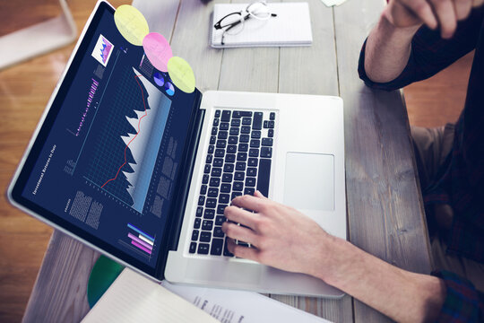 Hands of caucasian businessman sitting at desk, using laptop with statistical data on screen