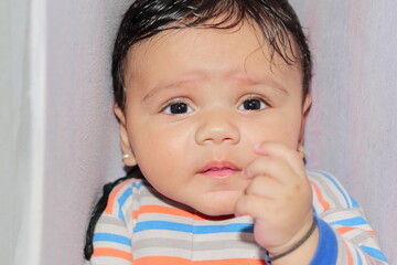 An indian little newborn innocent baby sleeping in the crib and looking at the camera