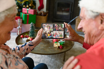 Caucasian senior couple in santa hats on christmas tablet video call with family