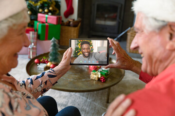 Caucasian senior couple in santa hats on christmas tablet video call with smiling friend