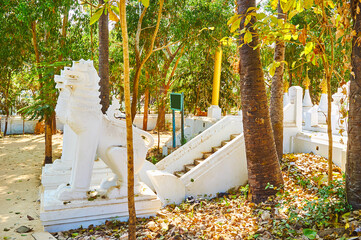 White chinthes in lush garden, Shwethalyaung Buddha Temple, Bago, Myanmar