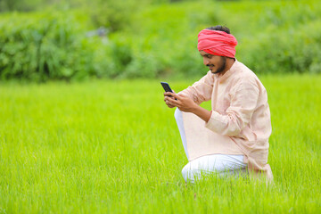 Naklejka na ściany i meble Indian farmer using smartphone at agriculture field.