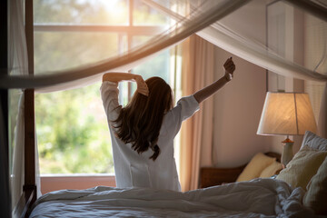 Back view of a blurry soft image of a woman with long hair is stretching relaxing on a sunny morning in a cozy room at a Resort hotel with green nature outside. Weekend, travel, and Holliday concept