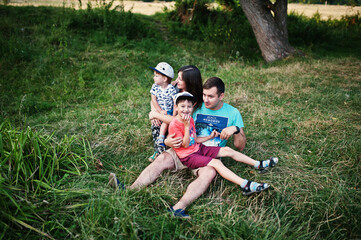 Fototapeta premium Happy young family: mother, father, two children son on nature having fun.