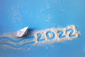 wish for the new year ship made of paper on a blue background with the numbers 2022, the concept of travel in the new year