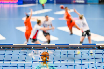 Detail of handball goal crossbar with net and women handball match in the background. - obrazy, fototapety, plakaty