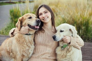 beautiful girl hugs two golden retrievers. Outdoor