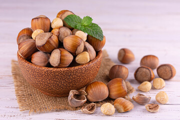 Hazelnut. Organic hazelnuts in a wooden plate on a white wooden background. Close-up of nuts.