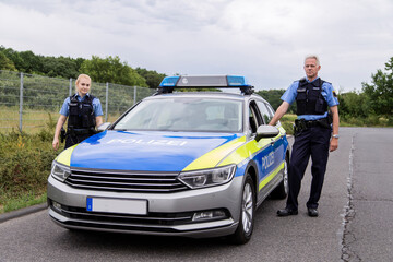 Polizisten bei Polizeiauto