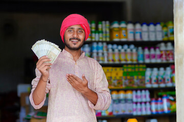 indian farmer showing money at fertilizer shop