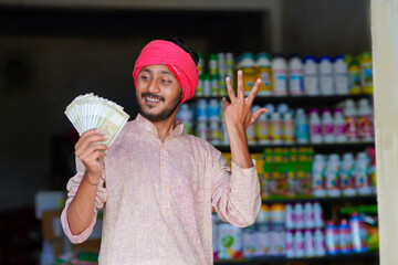 indian farmer showing money at fertilizer shop