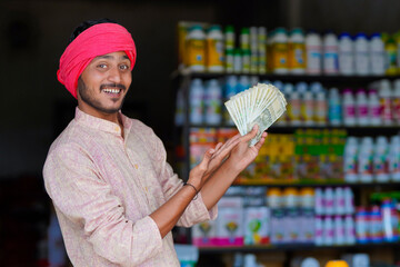 indian farmer showing money at fertilizer shop