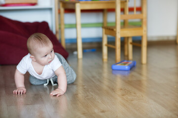 Baby 6 months old crawls on the floor in the nursery, children's development center