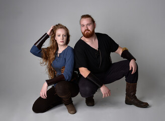 Full length  portrait of red haired  couple, man and woman wearing medieval viking inspired fantasy...