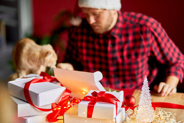 Vet Man in Santa hat and cat in hand making greeting card for New Year and Christmas