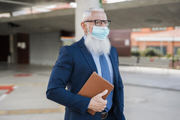 Senior hipster business man wearing safety mask at bus station - Focus on face