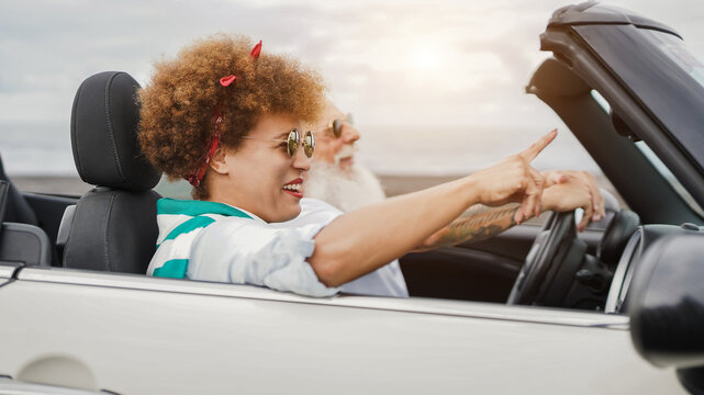 Happy senior couple having fun in convertible car during summer vacation - Focus on african woman face