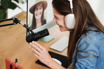 Influencer woman streaming live podcast with mobile phone at home - Focus on hand