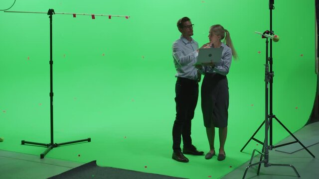 Female and Male Colleagues Wearing Casual Clothes Talking, Using Laptop Computer in Green Screen Mock Up Chroma Key Studio. Business, Corporate Office, Work, Technology Concept.