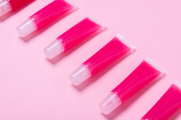 Lot of homemade lip glosses on pink background