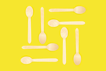 Bamboo disposable picnic spoons on a yellow background. Eco conservation concept