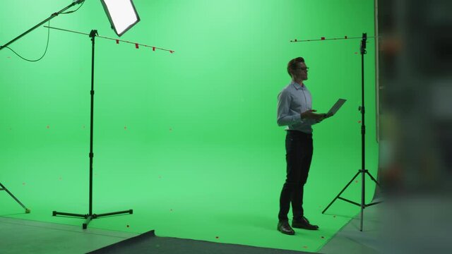 Handsome Young Man Wearing Casual Jeans and Shirt, Using Laptop Computer in Green Screen Mock Up Chroma Key Studio. Business, Corporate Office, Work, Technology Concept.