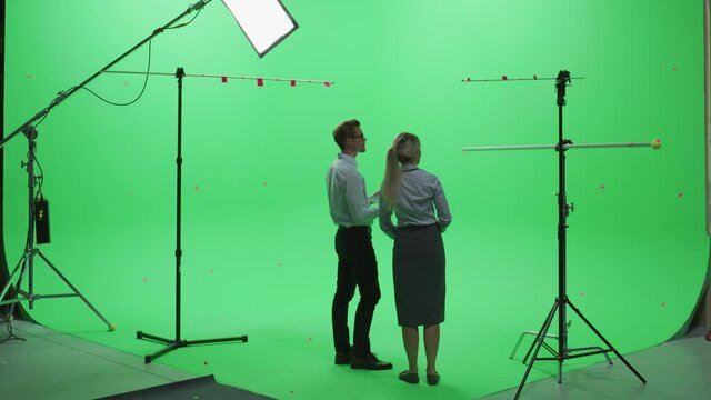 Female and Male Colleagues Wearing Casual Clothes, Standing with Their Backs - Using Laptop Computer in Green Screen Mock Up Chroma Key Studio. Business, Corporate Office, Work, Technology Concept.