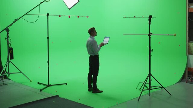 Handsome Young Man Wearing Casual Jeans and Shirt, Using Laptop Computer in Green Screen Mock Up Chroma Key Studio. Business, Corporate Office, Work, Technology Concept.