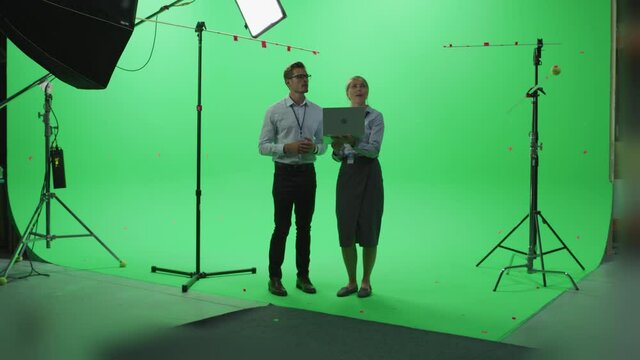 Female and Male Colleagues Wearing Casual Clothes Talking, Using Laptop Computer in Green Screen Mock Up Chroma Key Studio. Business, Corporate Office, Work, Technology Concept.