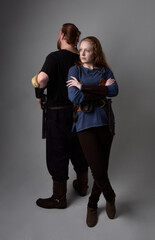 Full length  portrait of red haired  couple, man and woman wearing medieval viking inspired fantasy costumes, standing romantic intimate poses, isolated on white  studio background.