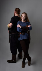 Full length  portrait of red haired  couple, man and woman wearing medieval viking inspired fantasy costumes, standing romantic intimate poses, isolated on white  studio background.