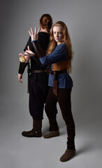 Full length  portrait of red haired  couple, man and woman wearing medieval viking inspired fantasy costumes, standing romantic intimate poses, isolated on white  studio background.