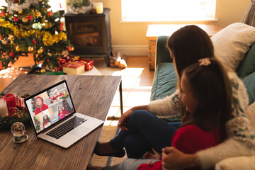 Caucasian mother and daughter in santa hat on christmas laptop video call with friends